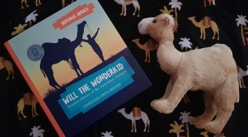 A hardcover book titled 'Will the Wonderkid' next to a soft camel toy