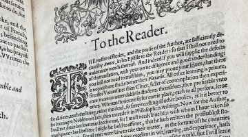 A book opened to a page of black text and visual embellishments. The heading on the page reads 'To the Reader'.