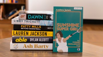 Stack of books on a table featuring 'My Dream Time' by Ash Barty, 'Able' by Dylan Alcott, 'My Story' by Lauren Jackson, 'Patty Mills' by  Boti Nagy, 'Beneath the Surface' by Libby Trickett and 'Dawn' by Dawn Fraser. Leaning against the stack is 'Sunshine Super Girl: the Evonne Goolagong Story' by Andrea James.
