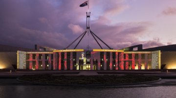 Parliament House at sunset, lit up with an image of Queen Elizabeth II and the words 'In memoriam'.