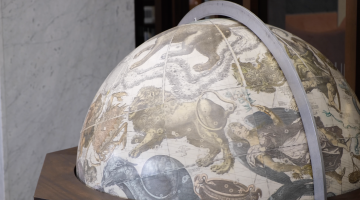 Large globe with mythological images, rather than geography, on it including a lion, serpents and mythological heroes