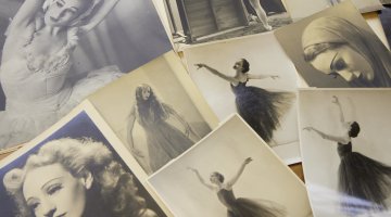 Photographs spread on a table, of a woman throughout her career in ballet, including photos of her dancing and portraits
