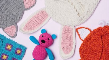 A flat lay of several different crocheted children's items including toys and clothing.