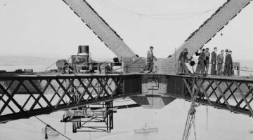 Group of men standing on a metal dirgle during the construction of the Sydney Harbour Bridge
