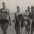 Four women lifesavers carrying a fifth woman in from the beach