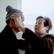A woman helps her husband put on his winter hat