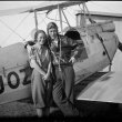 Two people pose in front of an aircraft