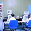 Two women in lab coats sit at computers