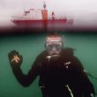 Man in scuba suit underwater near boat