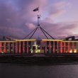 Parliament House at sunset, lit up with an image of Queen Elizabeth II and the words 'In memoriam'.