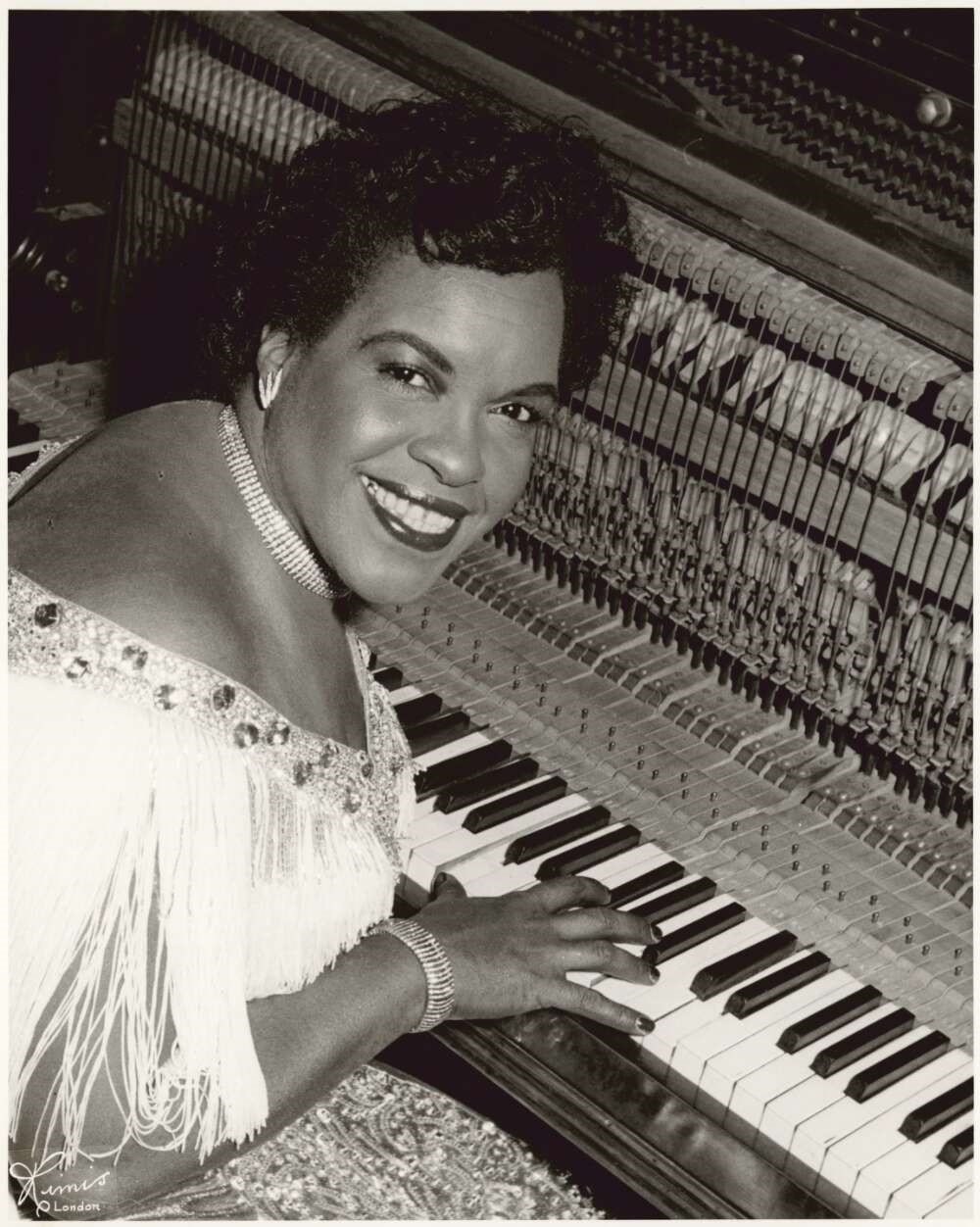 Black and white photograph of a woman over a piano