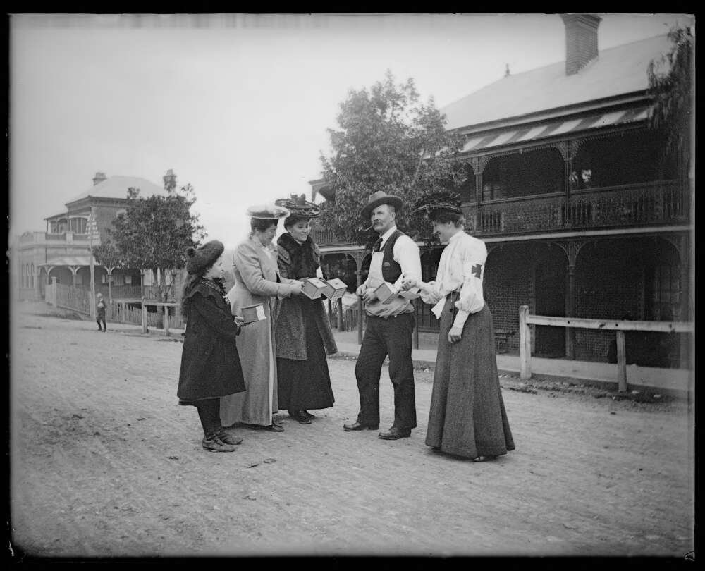 Black and white photograph of charity collectors speaking with members of the public on an open outdoor street