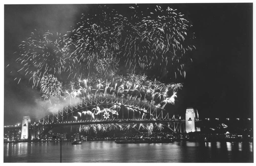 Black and white photograph of a fireworks display over Sydney Harbor Bridge