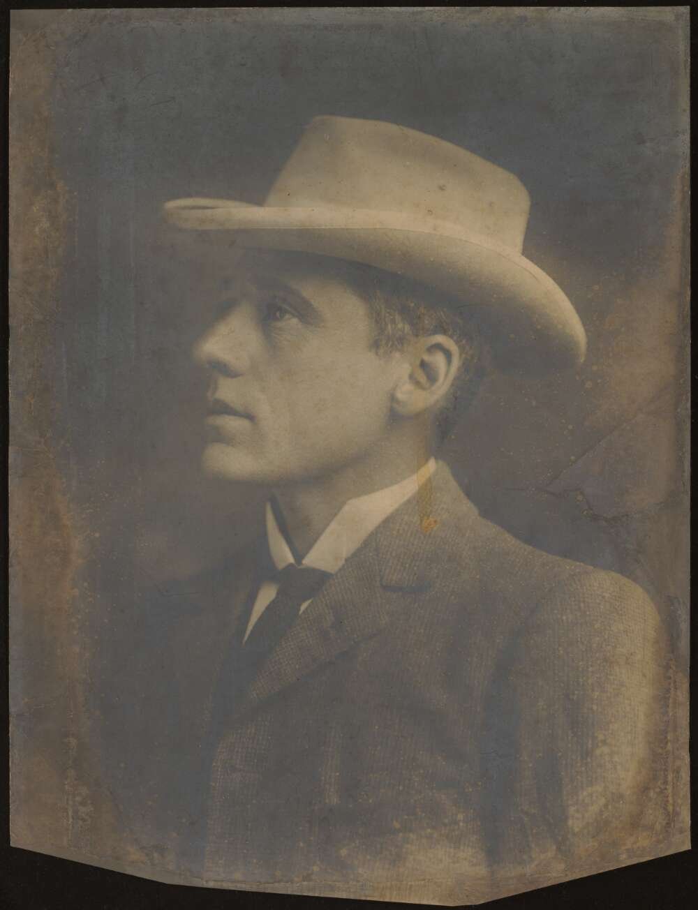A photograph of Australian poet Banjo Paterson in side profile. He wears a hat and a suit jacket.