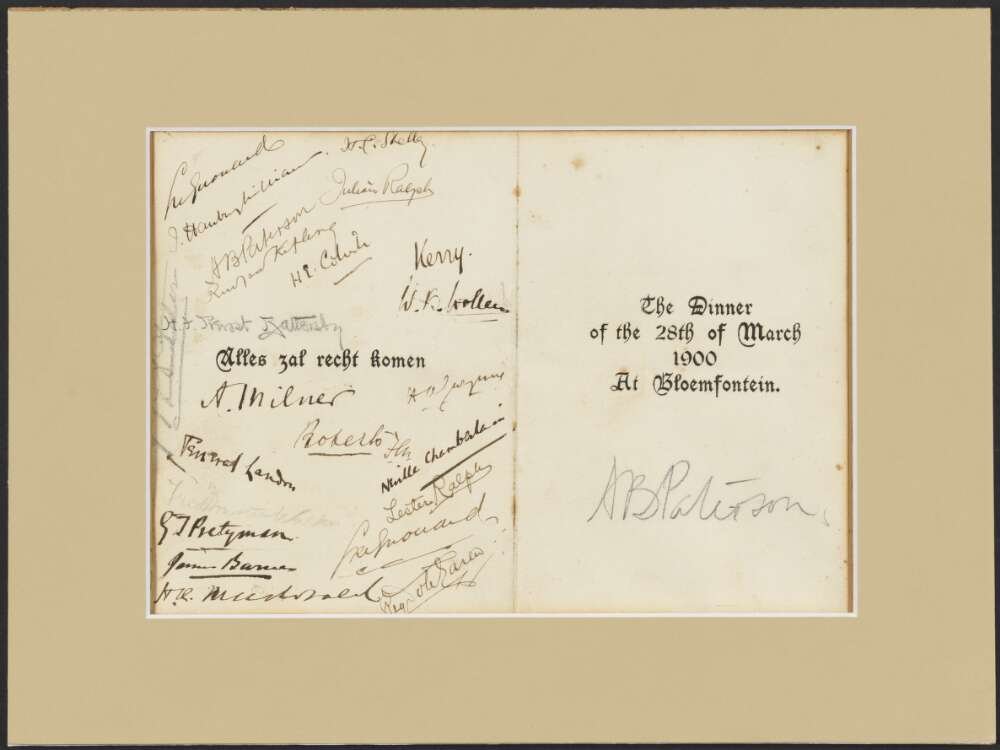 A paper dinner menu is obscured by a number of handwritten signatures.