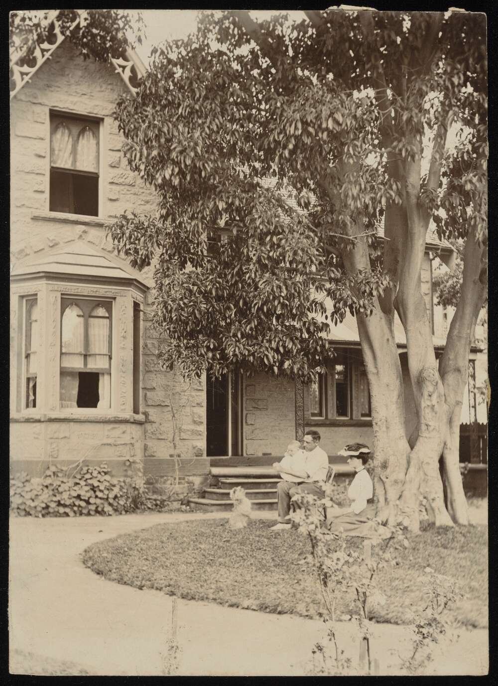 Photograph of a couple and two young children outside a large house