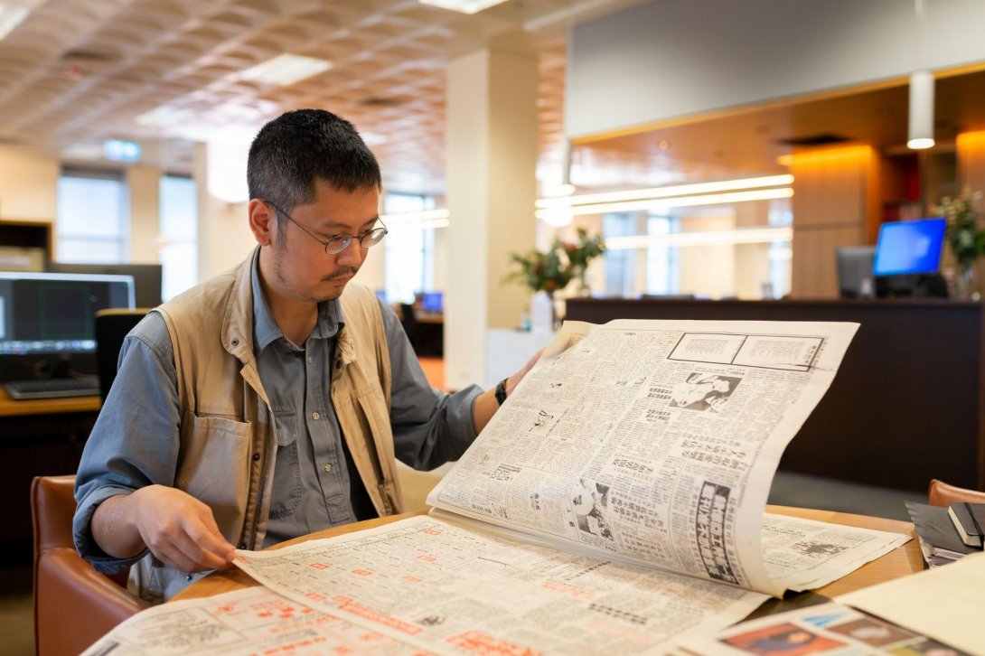 A scholar looks at a large format document in the Library's reading room.