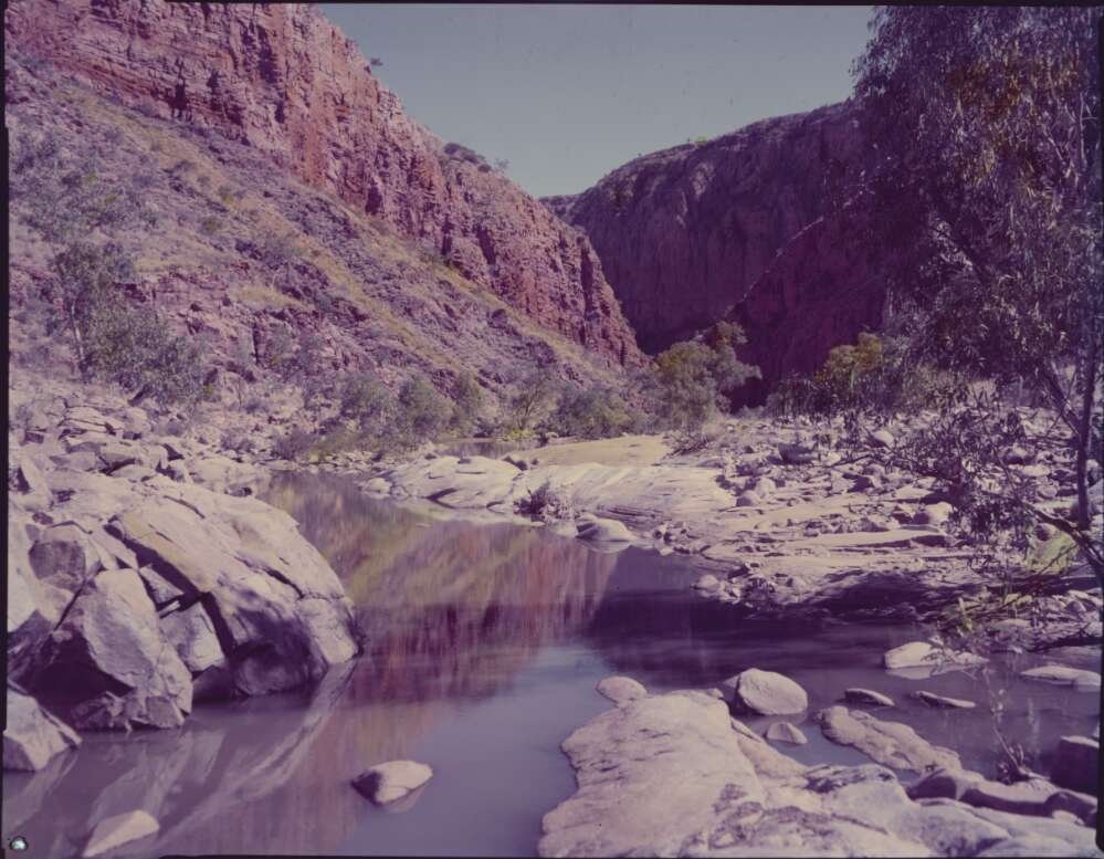 Rocky outcrops with a deep gorge between them; photograph is tinted a red tone