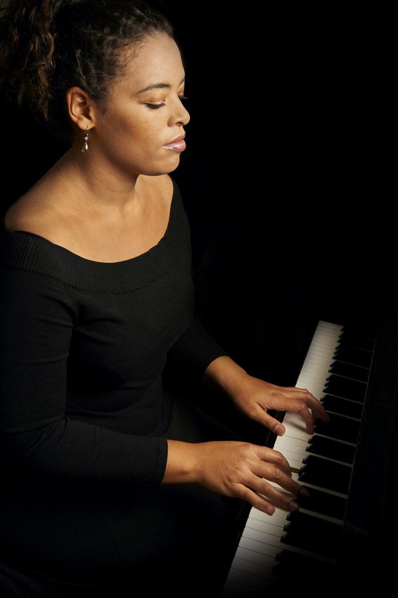 Dr Tonya Lemoh sits with her hands on the keys of a piano.