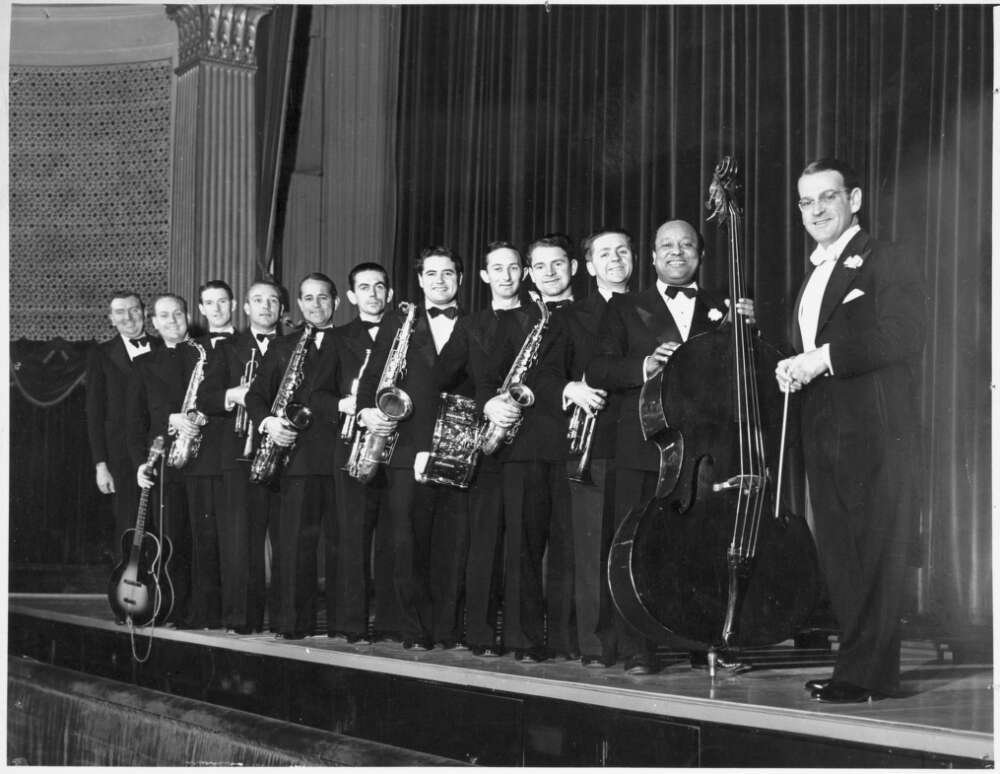A row of men in concert dress holding musical instruments