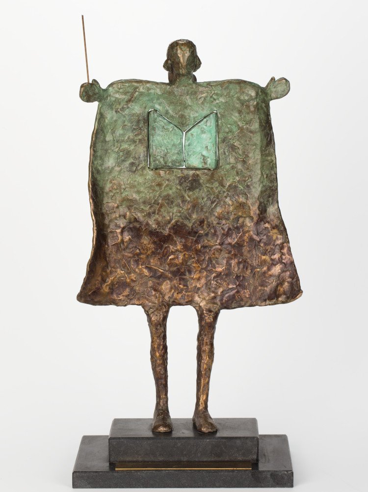 A bronze sculpture of a music conductor featuring an open book motif in the centre