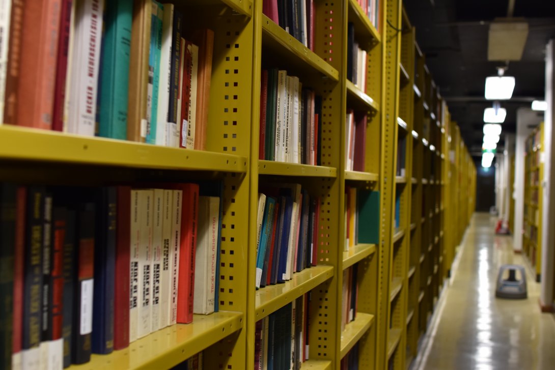 Metal shelves are full of bound volumes in many different colours
