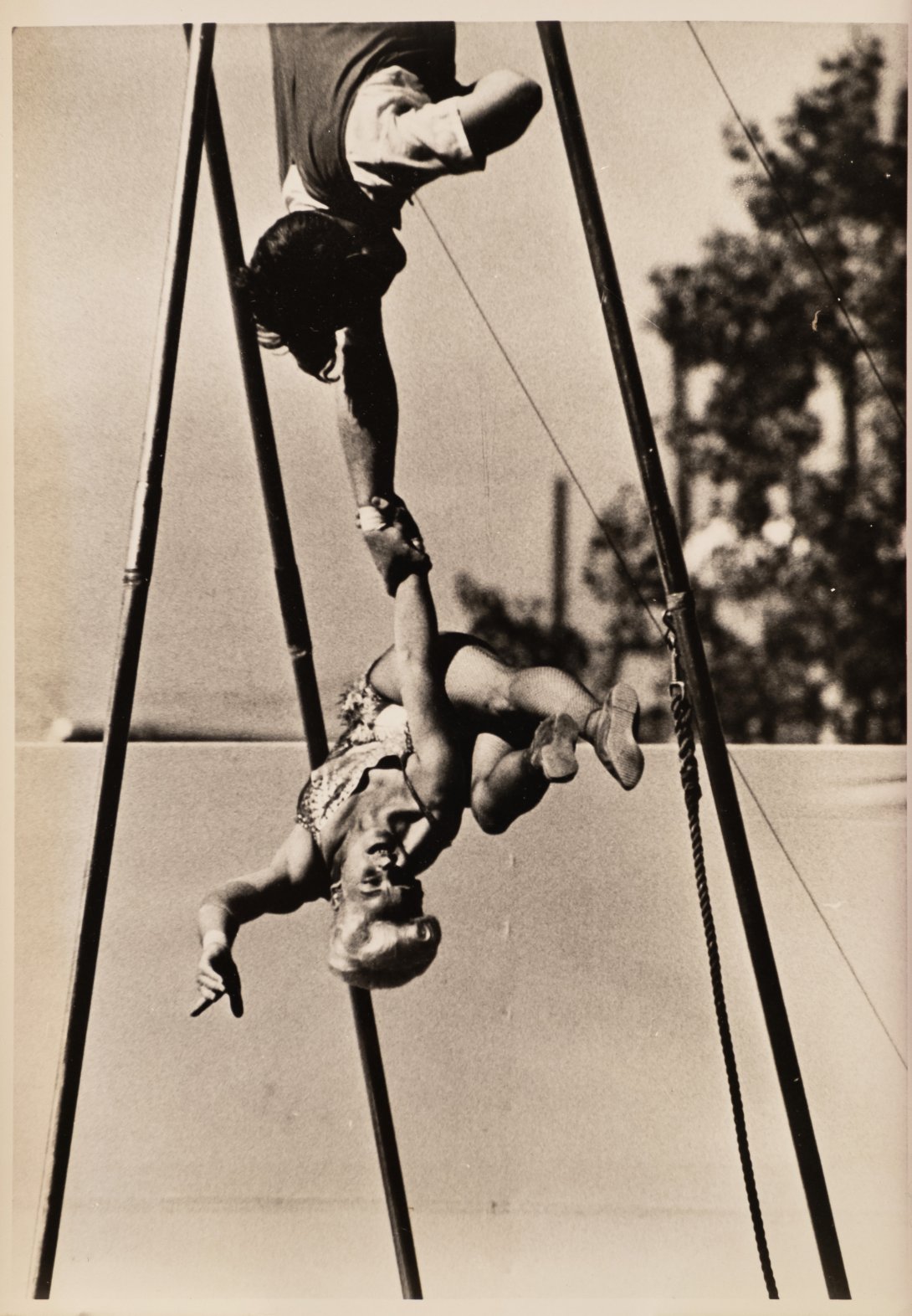 A photograph of two acrobatic entertainers performing an aerial trapeze act