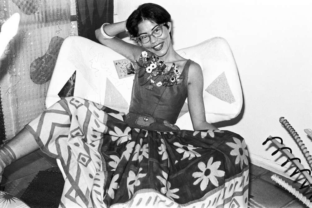 Black and white photograph of a woman, seated, with skirts featuring flowers