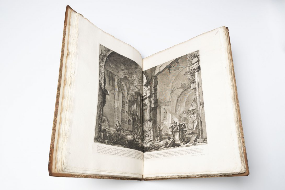 An old book opened to a black and white etching of a cathedral.
