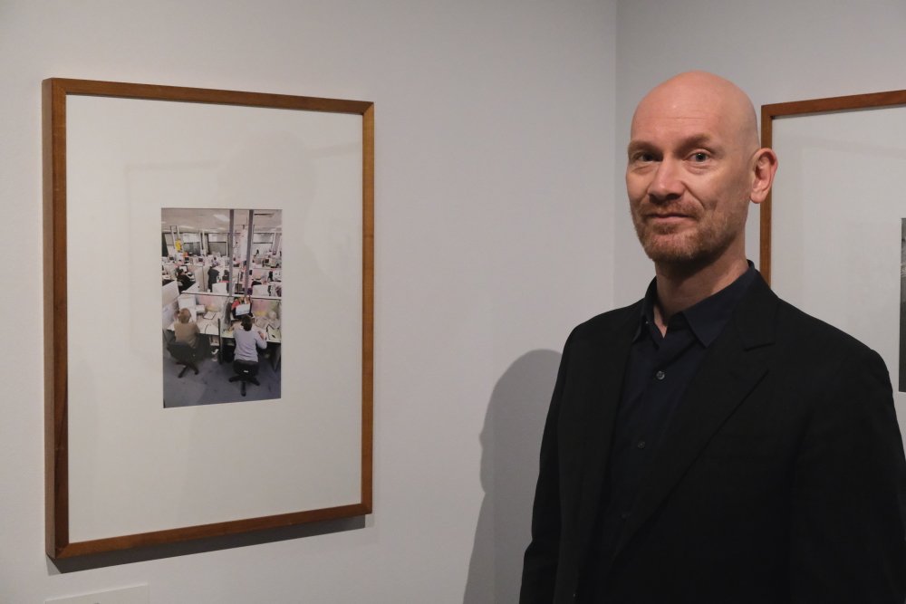 Dave Tacon stands next to one of his pictures in the exhibition gallery.