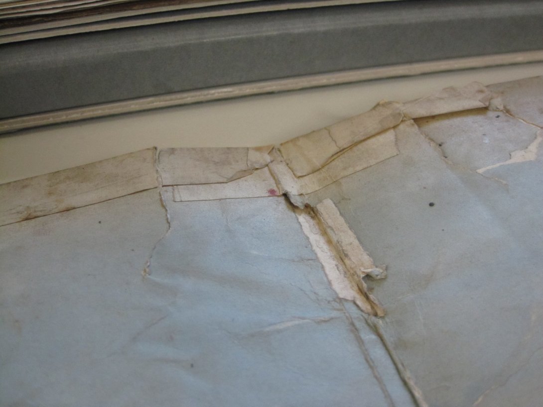 The spine and edge of an open old book patched together with cloth