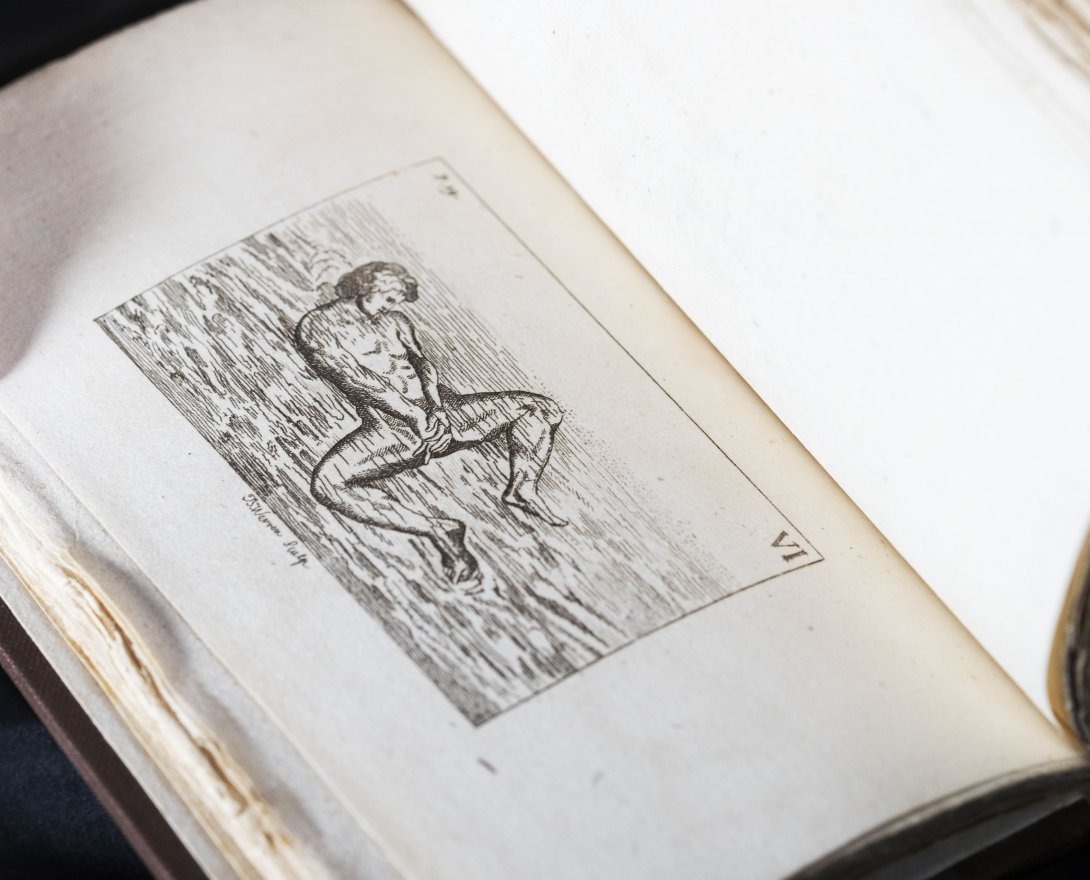 A rare book about swimming held open. Left side shows a black and white illustration of a person underwater with his knees bent. 