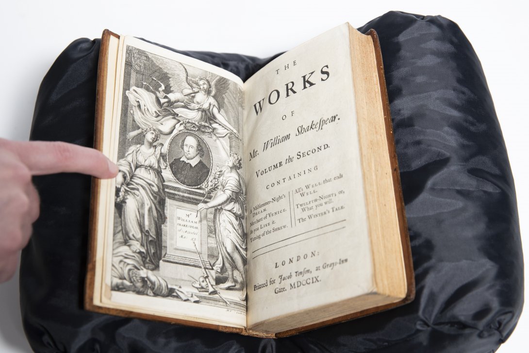 Old book open with one page showing black and white illustration of a shrine for Shakespeare and the other page reading 'The Works of Mr William Shakespear'  