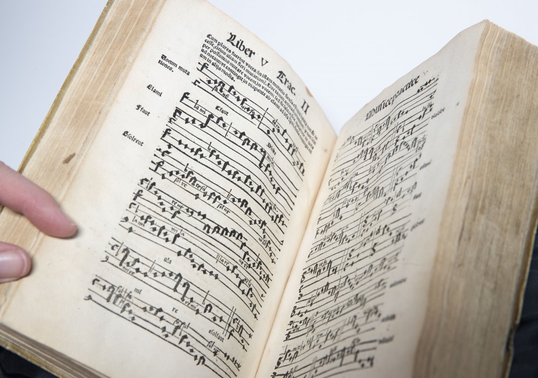 A rare book opened to two pages of sheet music.