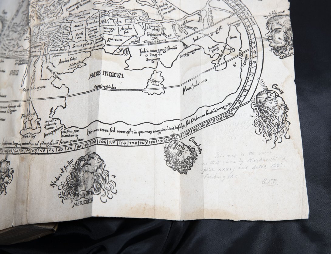 A page with an illustrated map with illustrated heads decorating the boarder. 