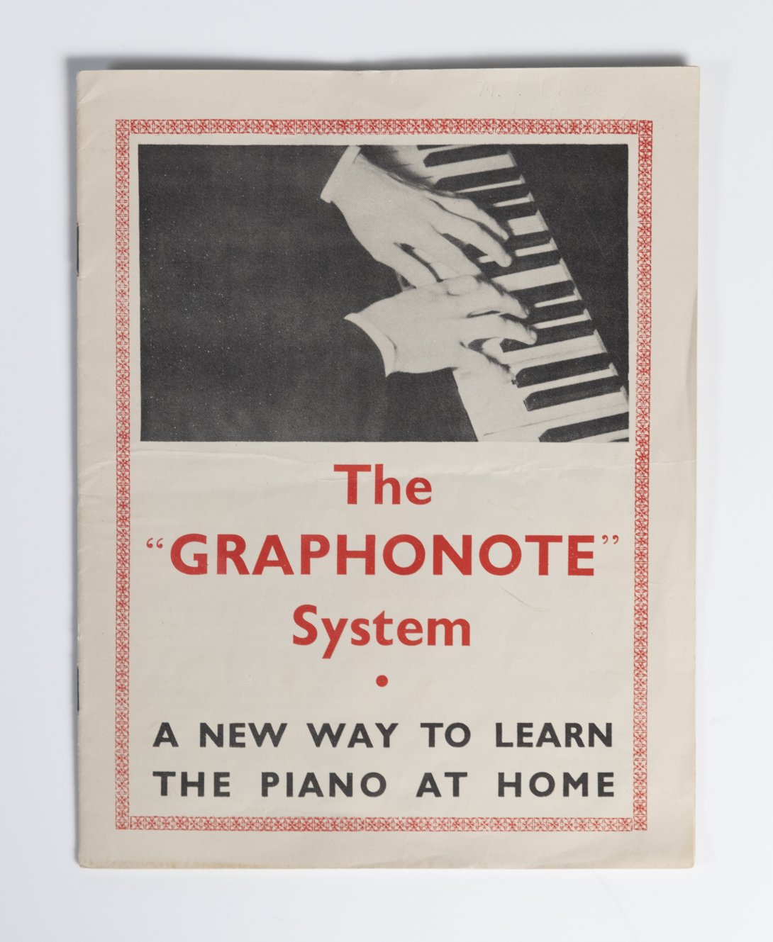 Closed booklet featuring red and black letters below an image of two hands playing a piano.