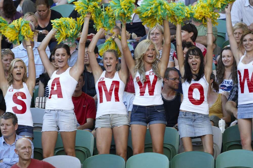 6 young women stand waving green and gold pompoms. Their matching tops, each with a single letter, spell out SAM WOW