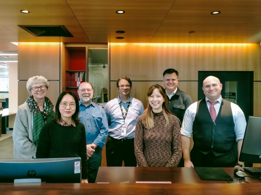 The National Library's Special Collections Research and Support Team, which is made up of three woman and four men, smiling and standing behind an information desk