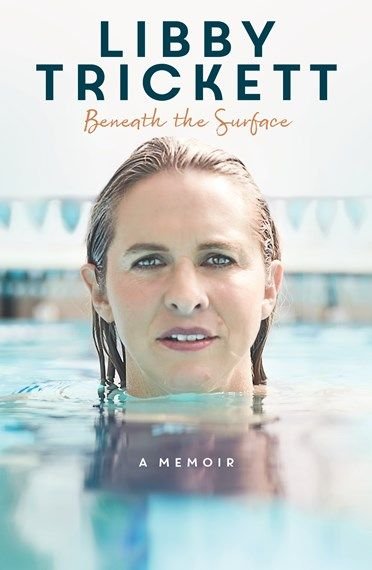 Woman submerged in water with just her head above the surface looking directly at the camera. text t the top reads 'LIBBY TRICKETT Beneath the Surface'