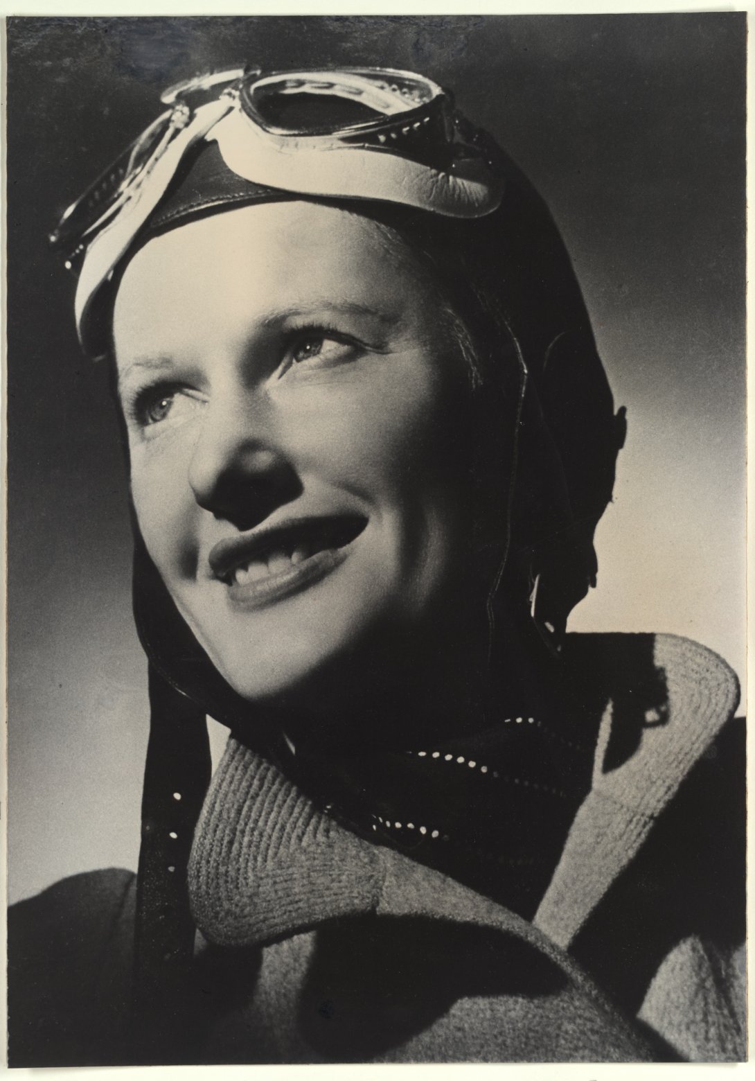 Portrait of a smilin woman wearing a pilot's cap and googles
