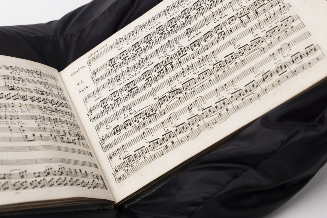 Open printed music score sitting on a black cushion