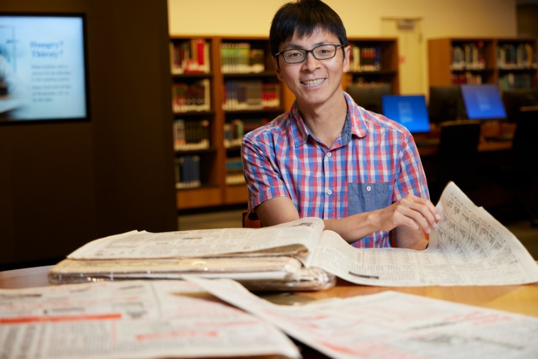 Dr Yao-Tai Li reading Chinese newspapers in the National Library of Australia reading room.