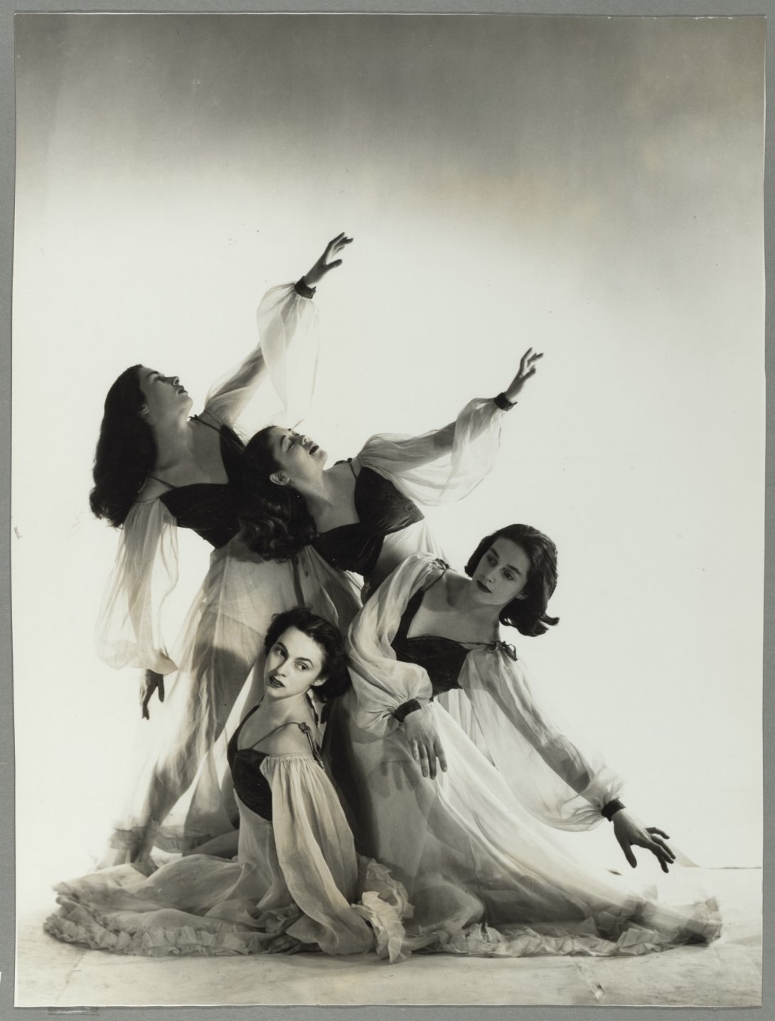 Four ballet dancers posing with their arms out and leaning in various directions