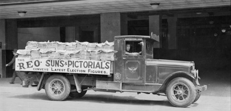 Old ute truck carrying newspapers. sign on truck says This reo runs &amp; picturial's converys lastest election figures