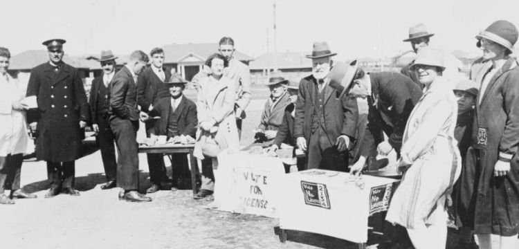 Several men and women around a voting booth in the 1920s