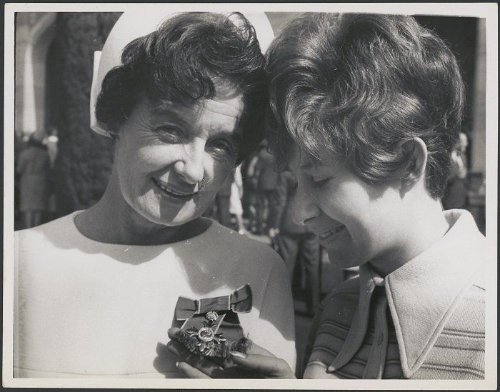black and white photograph of two women, Hazel de Berg and her daughter Diana, showing Diana admiring Hazel's new medal for her MBE