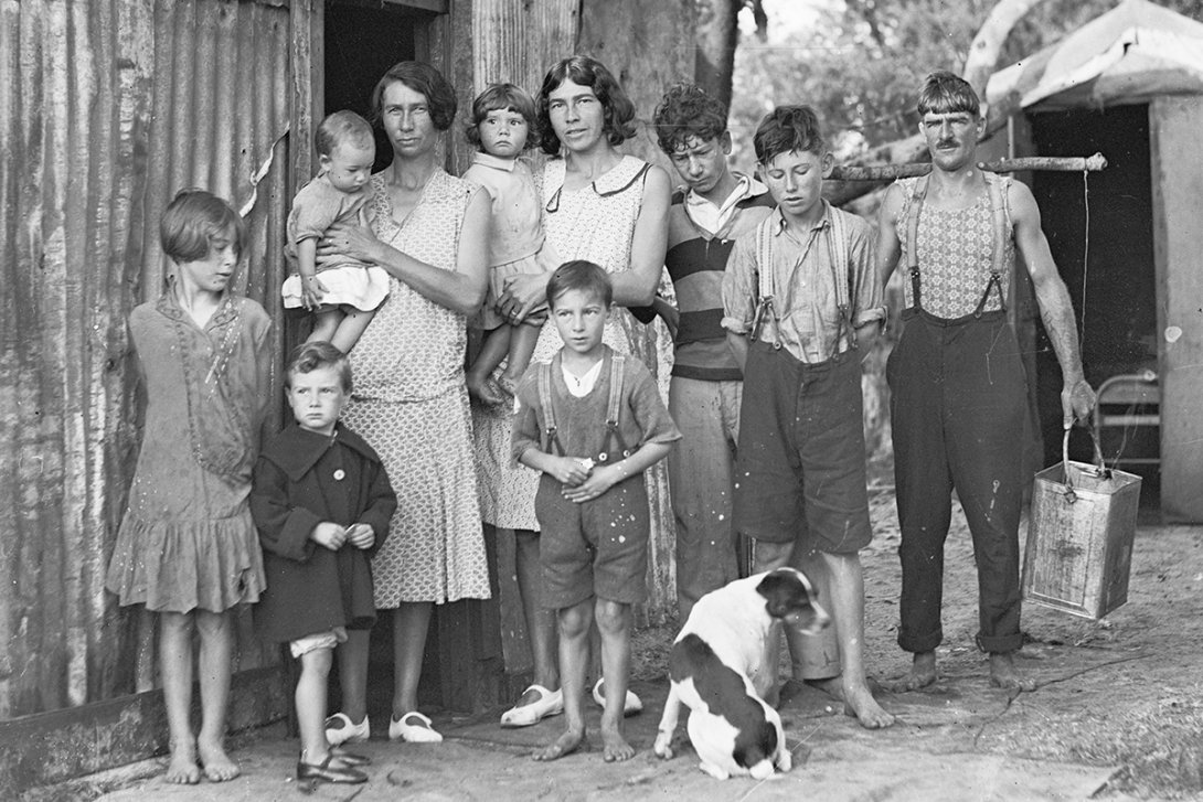 A large family stand in front of a corrugated structure with a dog at their feet
