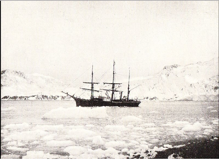A black and white picture of a ship sailing through ice with Antarctica in the background